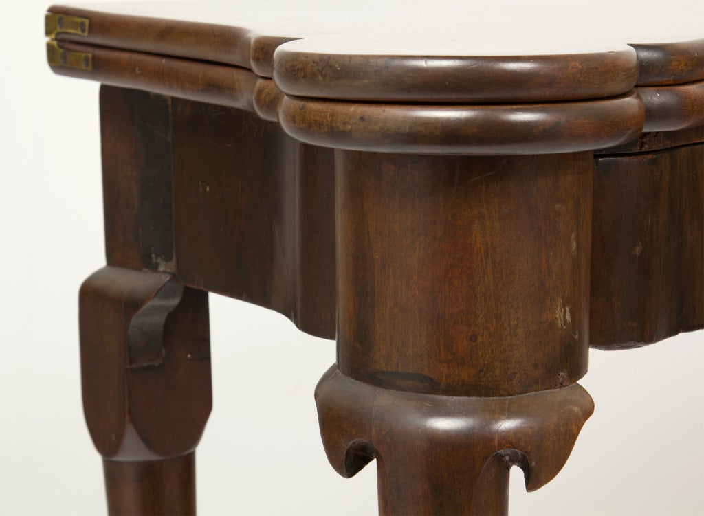 Early George III English red walnut game table, circa 1760. This table has a rare concertina support mechanism where the back legs fold out with matching apron so that the table looks the same from all four sides when open. With candle stands in the