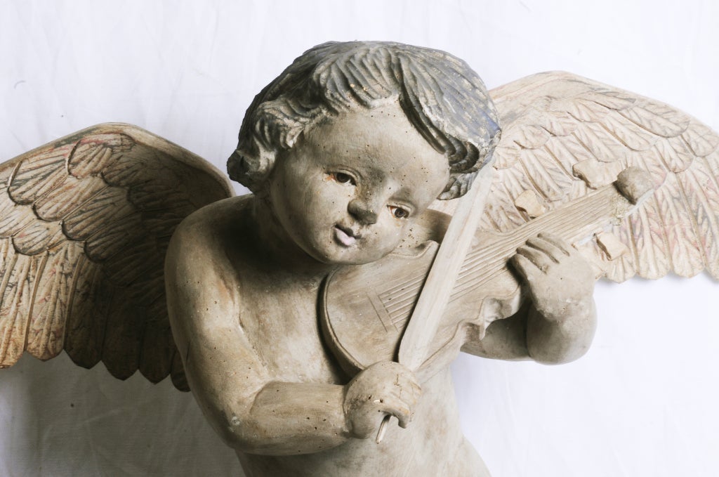 A charming large Spanish colonial carving of an angel.  With glass eyes, playing an instrument with a feather.  Big and great looking.