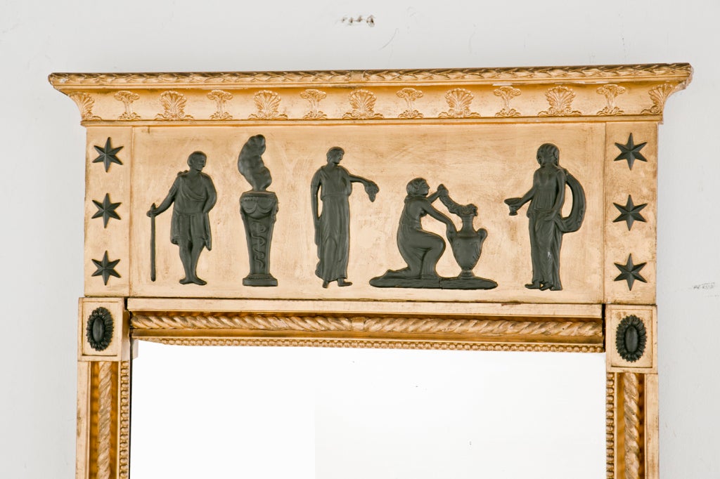 A handsome and well proportioned Neoclassical mirror made in Sweden during the first quarter of the 19th century.  Featuring well modeled classical figures in black over a water gilt ground.  The mirror framed by an inset rope twist.  The four
