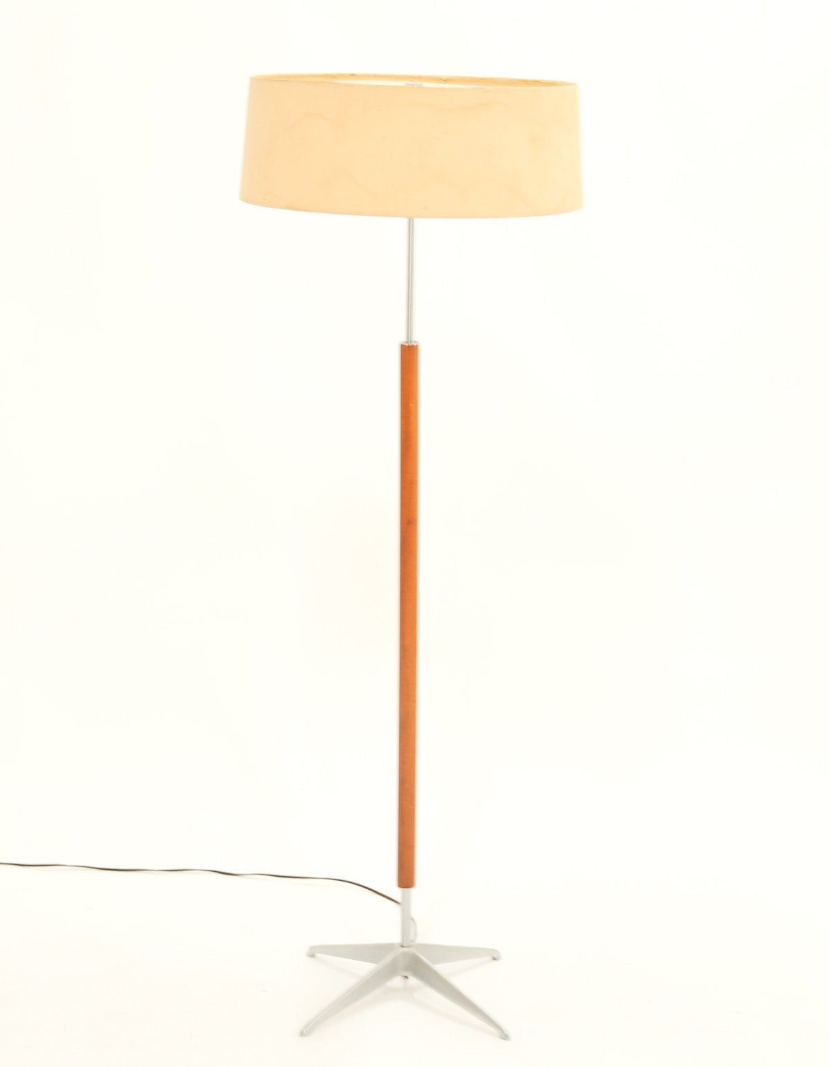 A aluminum and teak floor lamp by Gerald Thurston for Lightolier. The floor lamp comes with an aluminum star base and a walnut upright. The shade is original and needs to be reskin.