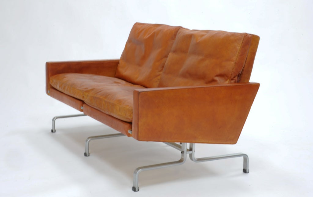 A handsome Kjaerholm love seat in original burnt amber leather. Arm height is 18.25