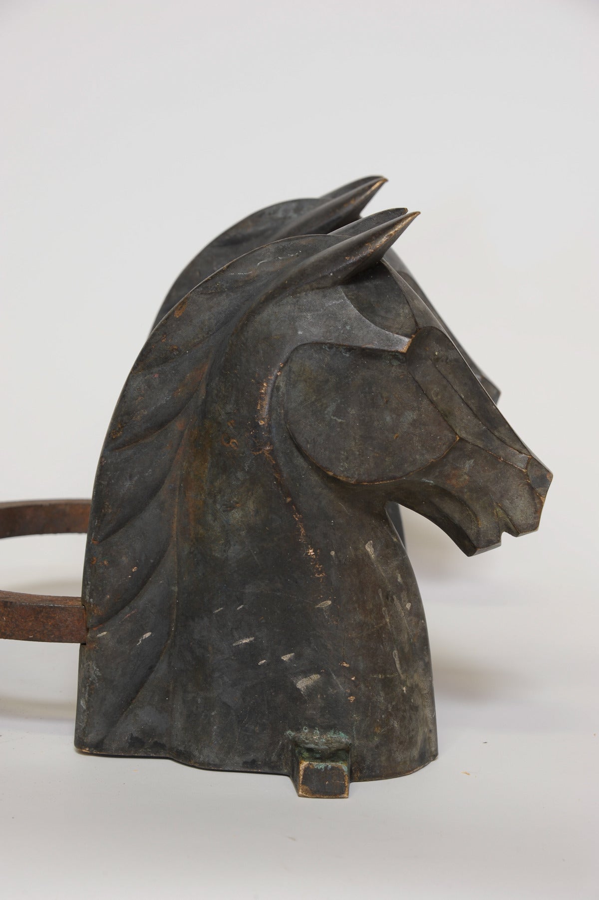A deeply patinated pair of andirons by Reynolds Jones. These modernist horse are demanding in both their style and scale. The heads are wonderfully patinated, they can be polished to a brass shine if desired for an extra fee.