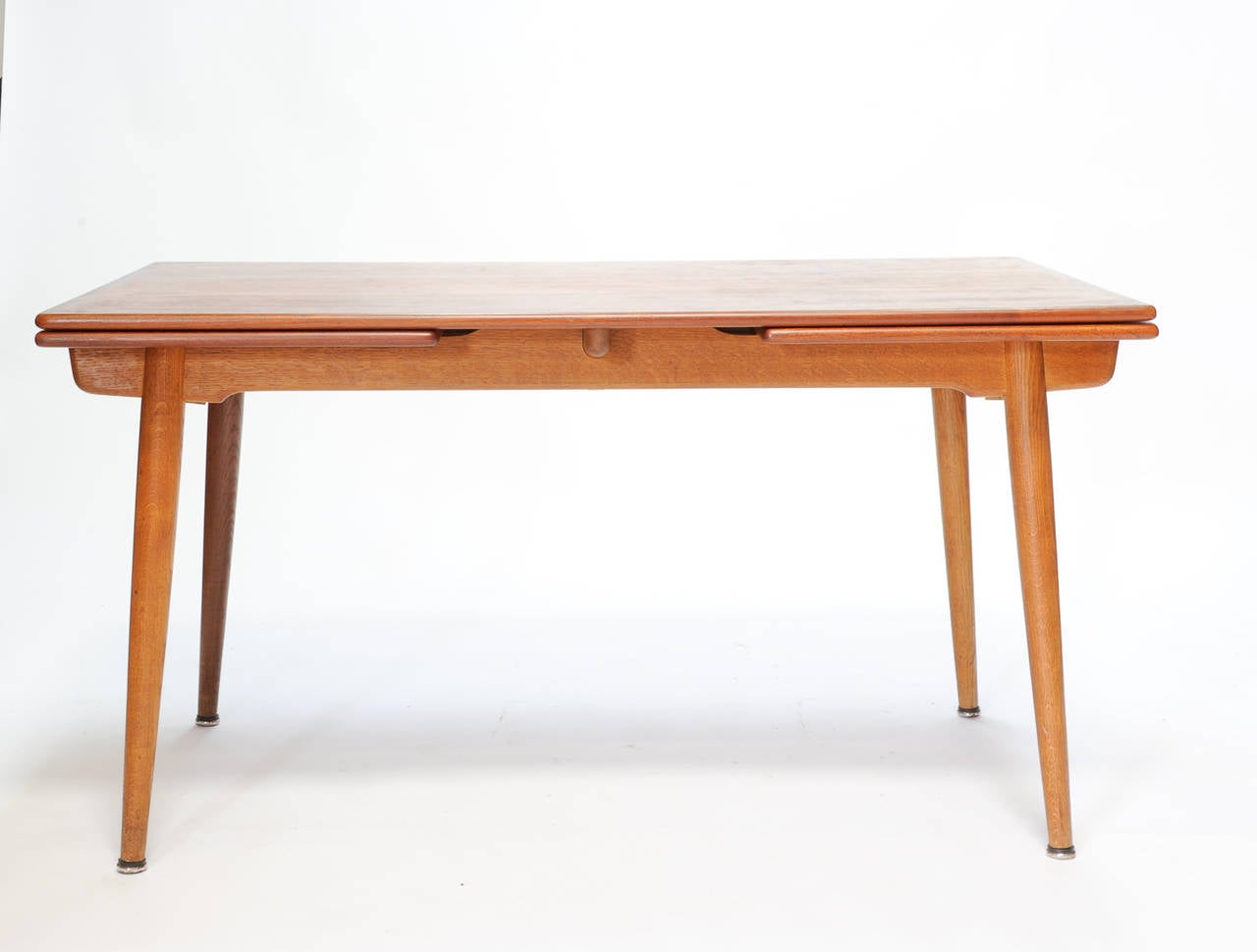 A beautiful and elegant dining table by Andreas Tuck and designer by Hans Wegner. The graining of the teak is stunning. Table has two 19.5 leaves. When the leaves are stored the top is 55