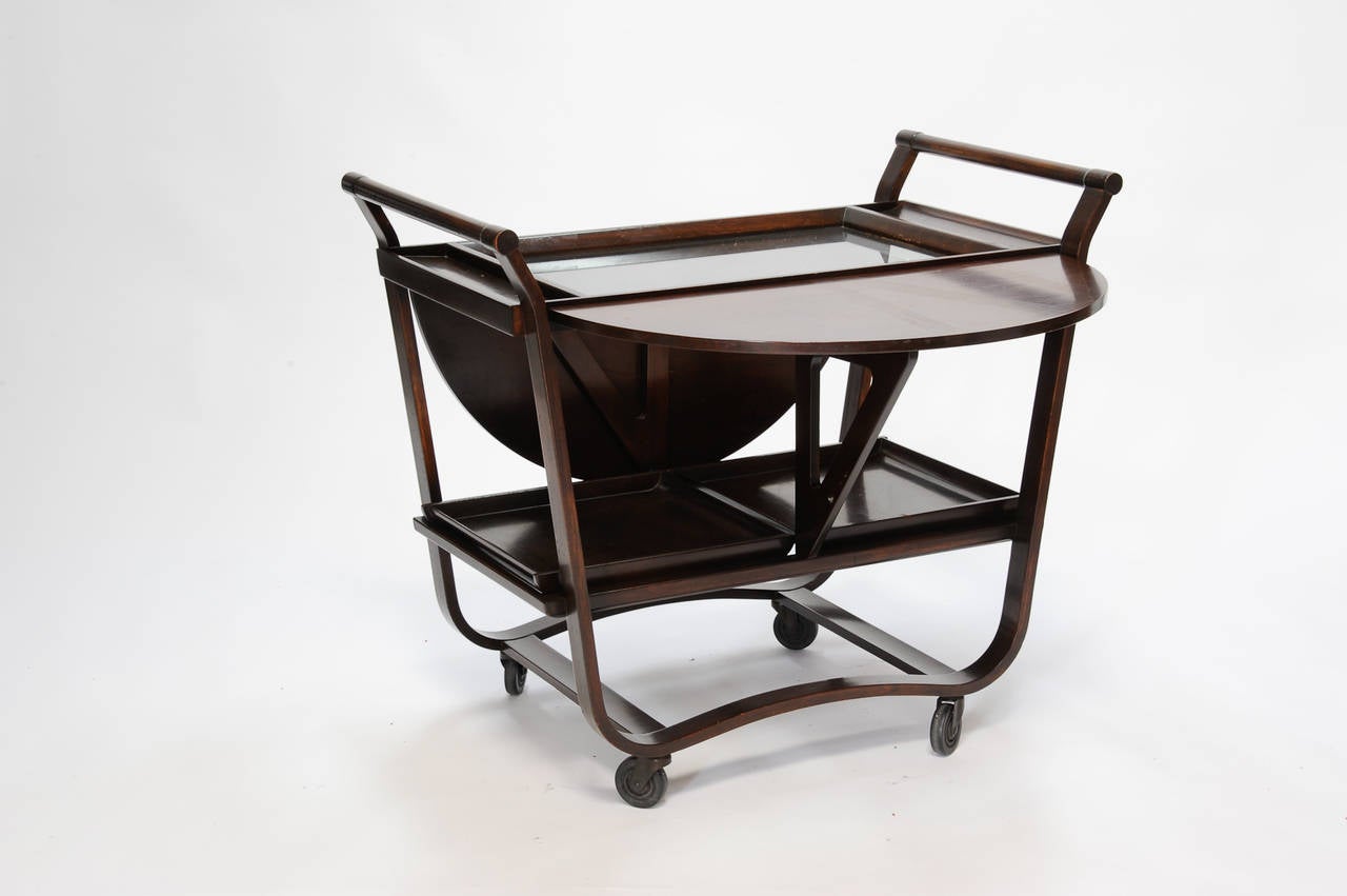 An early bar cart by Edward Wormley for Dunbar. The cart has all its part including the removable trays and glass top. The drop leaves are secure and sound.