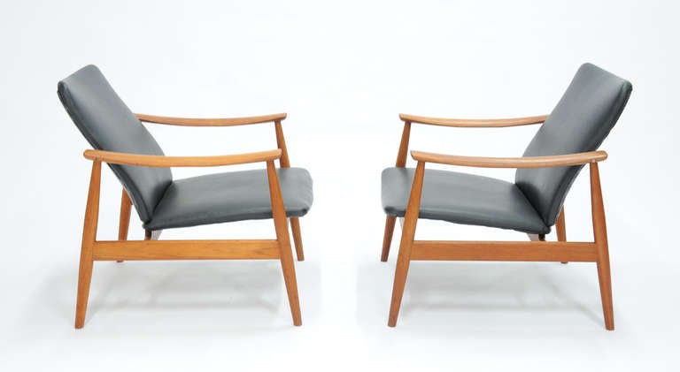 A handsome and simple Club Chairs for France And Sons by Danish Modern Master Finn Juhl.  In teak and faux leather are these club chairs with swiping arms. Arm Height is 22