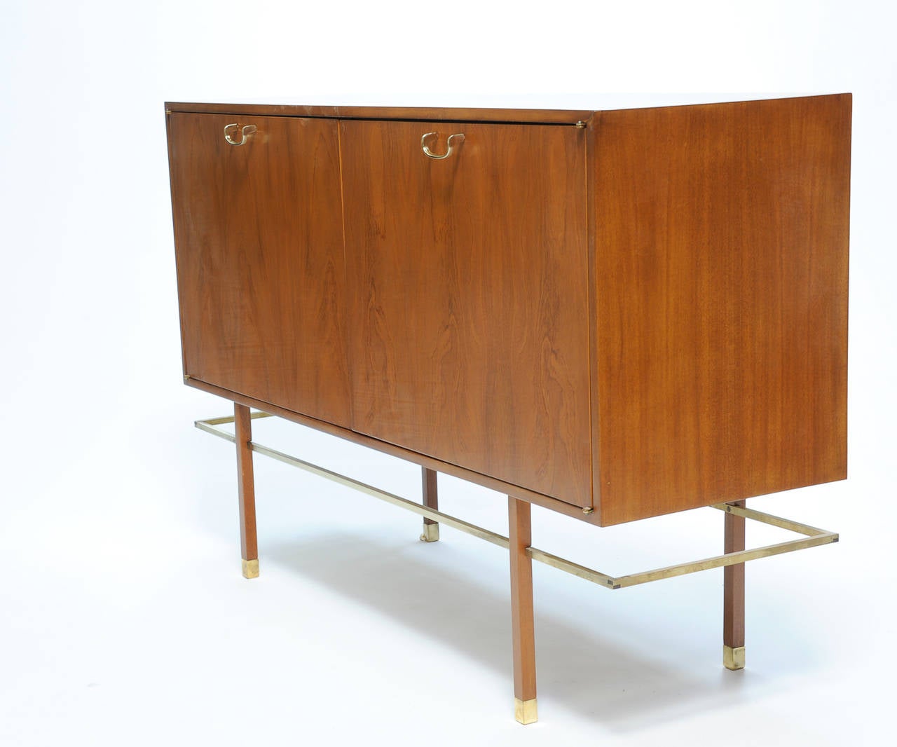 A two doors sideboard by Harvey Probber with a mahogany case and walnut doors. The sideboard features the signature Probber brass stretcher and feet.
Inside the cabinet is divided in four equal openings.

A handsome piece by a American modern