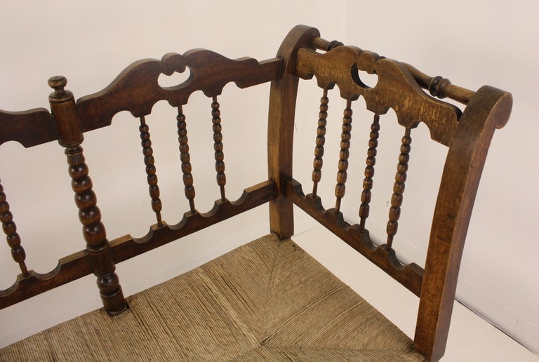 An antique bench from France with many charming details. There is considerable decorative carving, shaped rails and apron, and turned bobbin stretchers.  And lots of spindles. Old rush is in good condition. Reduced, NT