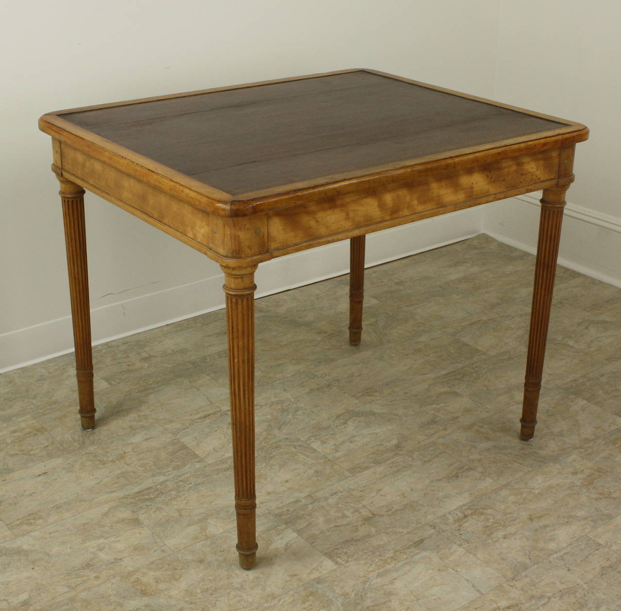 A very handsome writing table. The wood is beautiful, well-grained, and finished in a warm glow. The carved reeded legs, ending in a finished barrel shape, are elegant yet simple. Depending on size requirements, this might work anywhere in the home.