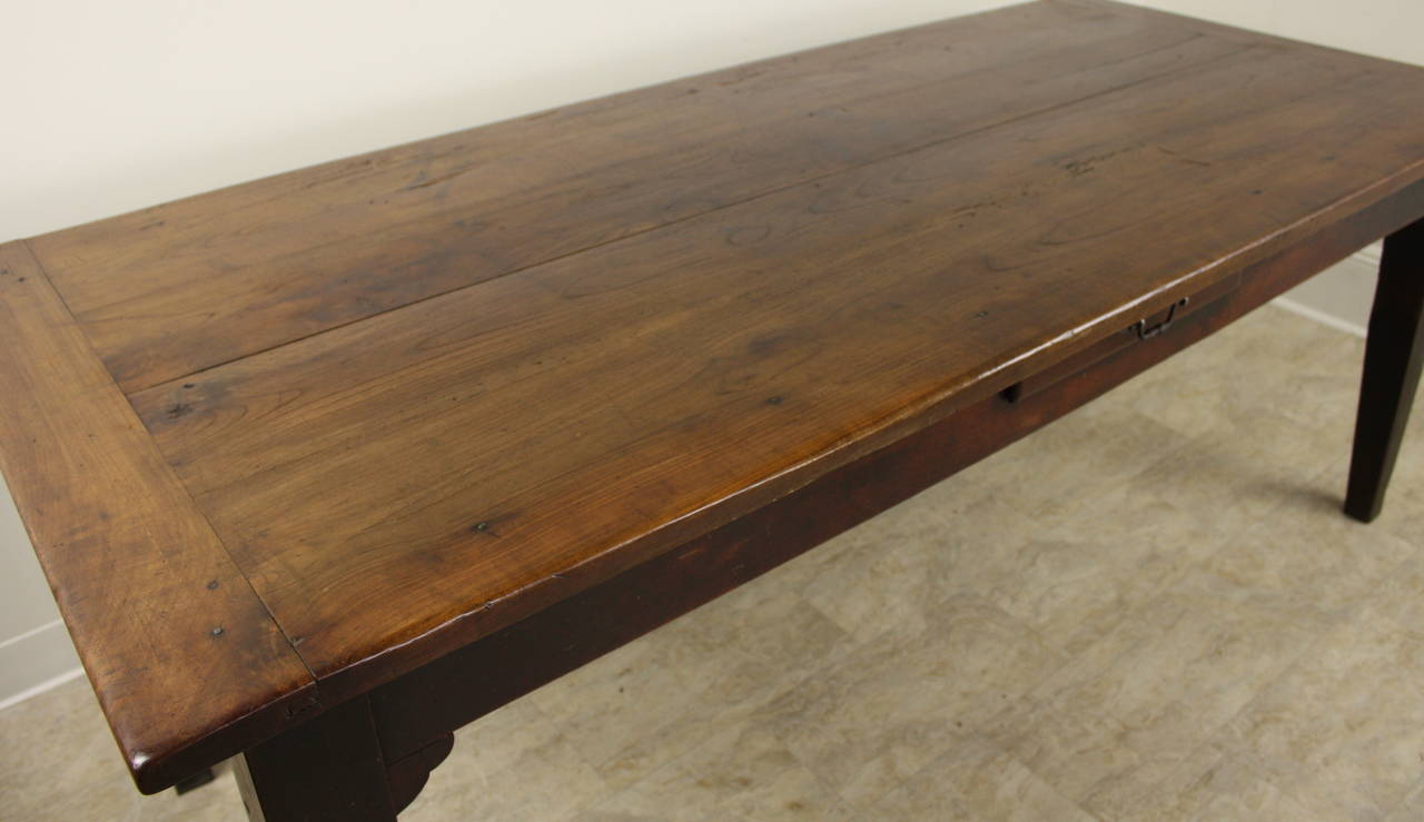A dramatic chunky cherry country farmhouse table, in a beautiful color with fine patina and grain.  The table has extra width, and a wonderful length. The legs are the classic tapered style and visually balance the strong top, which has lovely wide