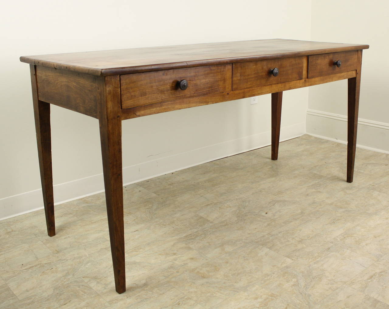 This is a lovely example of old cherry, the light and dark contrasting grain is typical and classic. The slender tapered legs add an elegant touch. Nice old hand turned knobs on the three drawers have been stained dark for an interesting visual