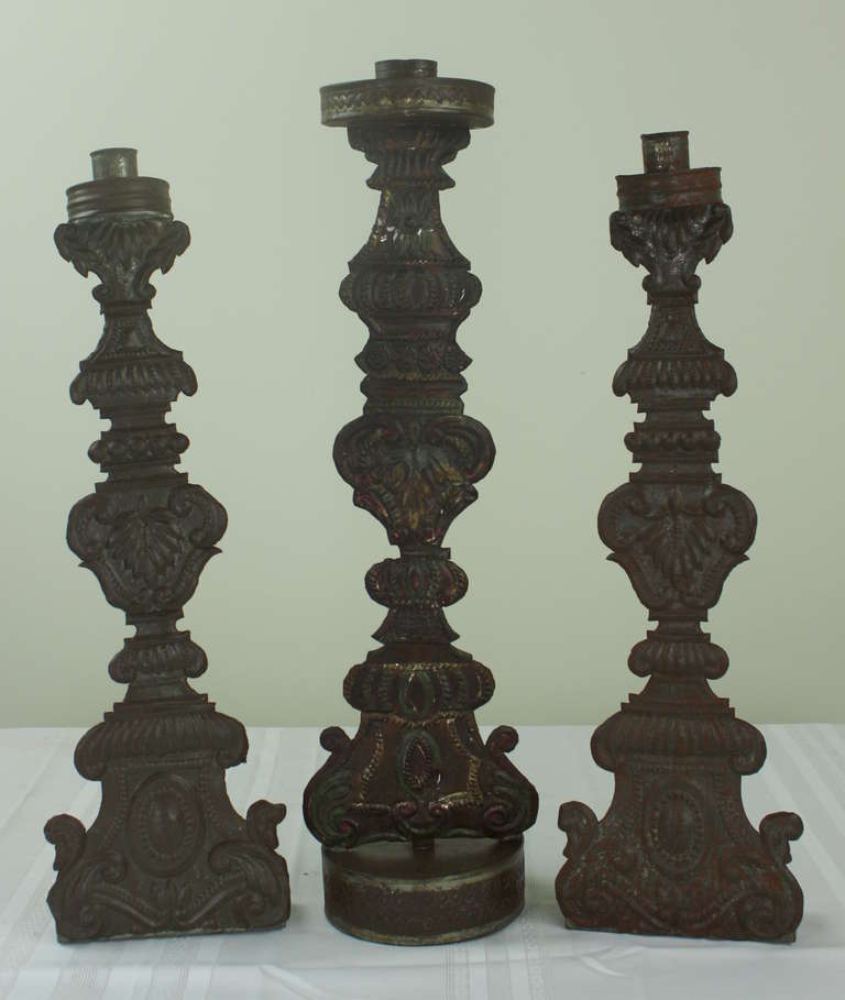 Damatically shaped early lightweight metal flat candlesticks, with round bases and tops,  Some old color, see image 2.  Dimensions below are for the larger piece.  The two smaller pieces measure 6W x 2.5D x 21.5H.