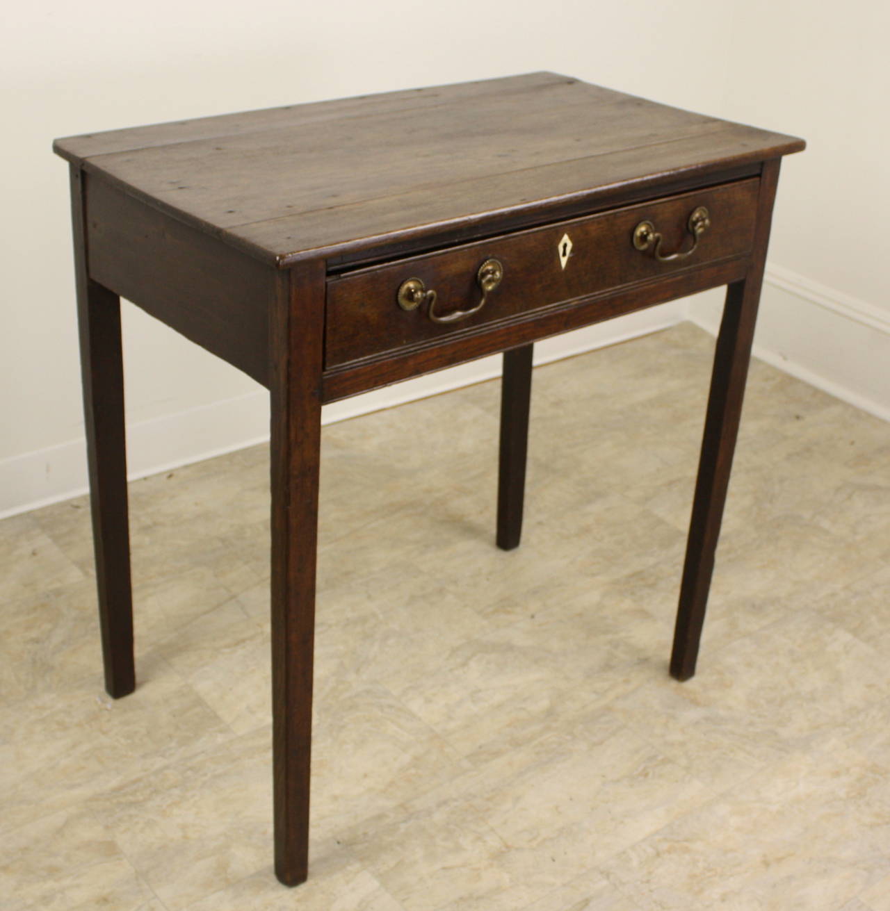 This early Welsh table is very classically lined, with lovely slender tapered legs and a large drawer across the front, with cock-beading edge, and a very nice escutcheon. The wood is a rich dark oak.  It would make a fine little desk, as the apron
