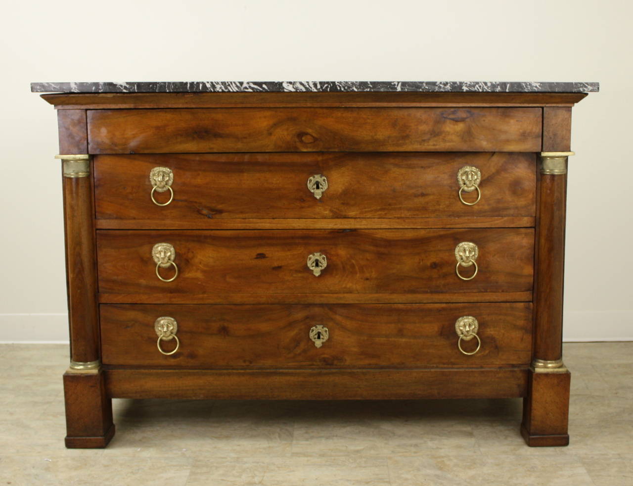 Stunning period commode.  The walnut is warm and glowing, complemented with ormolu handles and decoration.  The original marble is an appropriate veined black.  Overall, this is a very elegant piece.  Drawers slide smoothly.  Very fine.