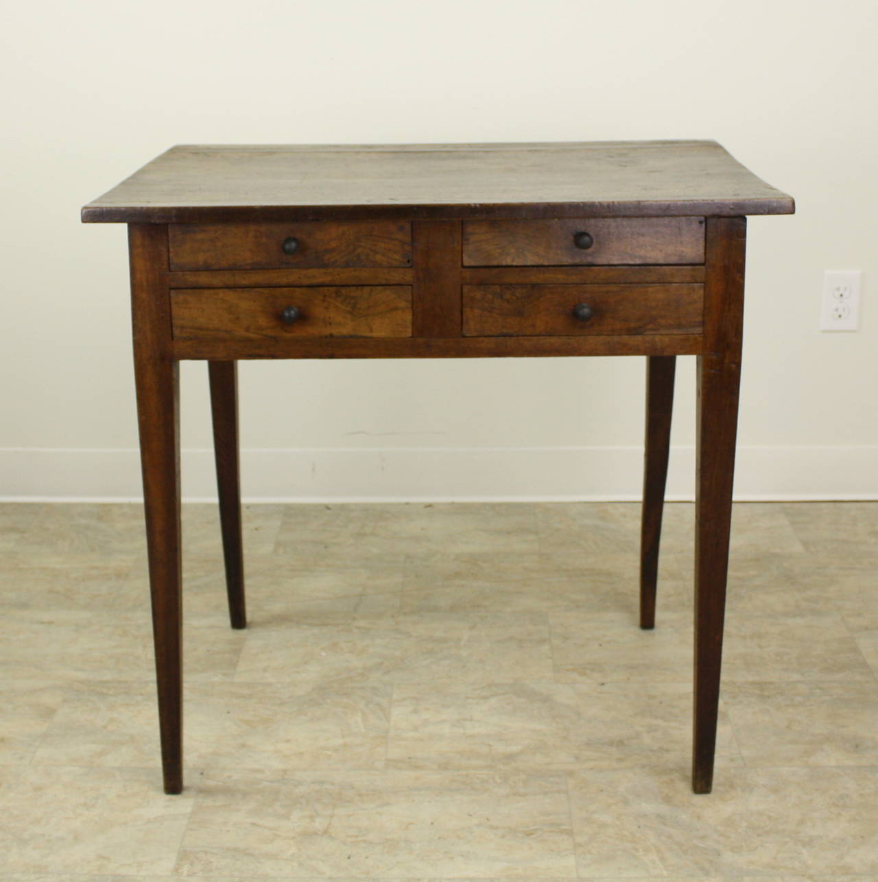 A very charming look.  This little end table is the right height for a lamp, and on its tapered slender farm table style legs, is quite elegant.  The four little drawers make an unusual configuration, a nice interesting difference.  The top, with