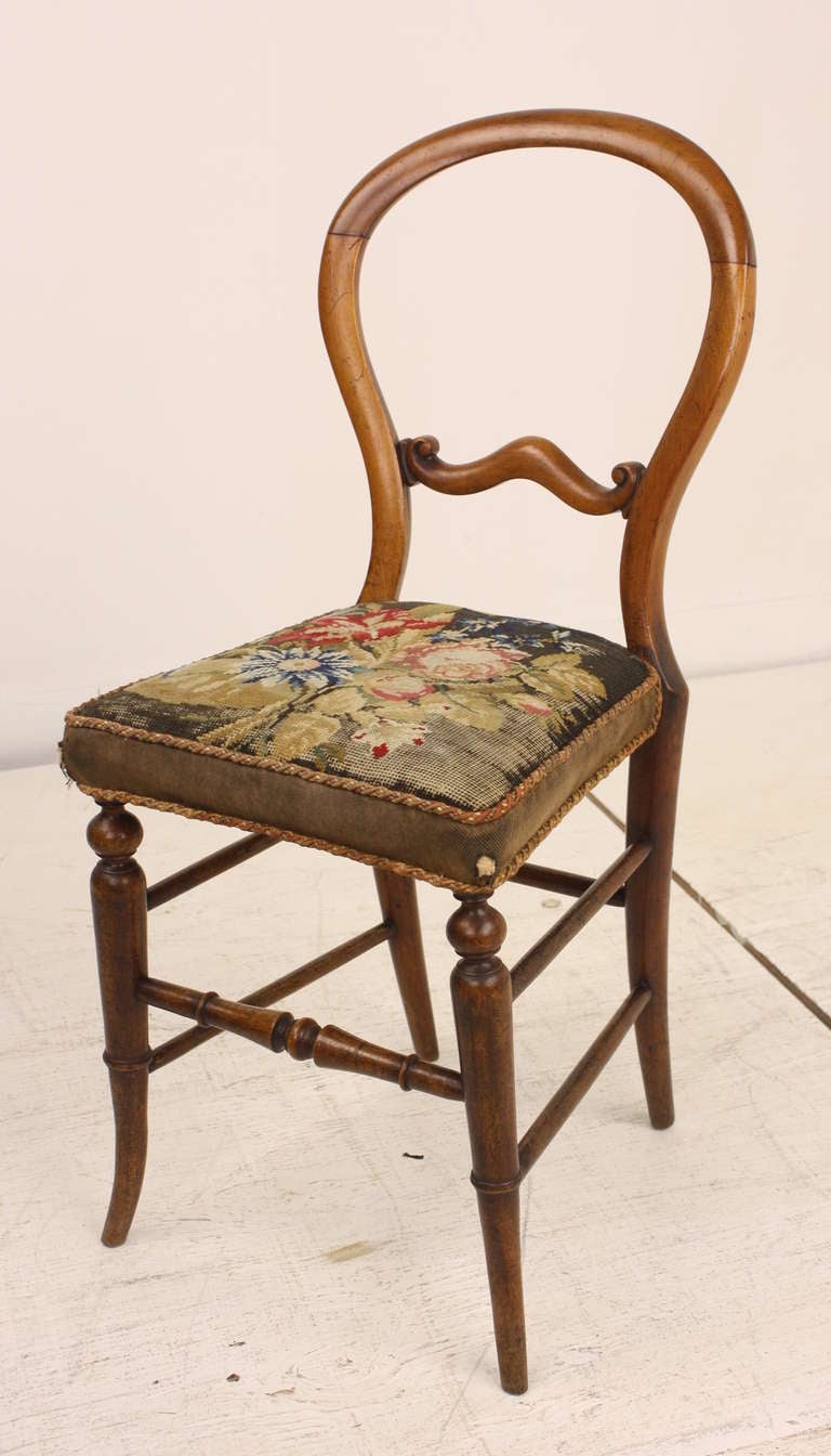 Lovely profile, the wood is in good condition with a glowing patina.  The turnings are excellent, obviously well made.  The needlepoint shows its age, but is charming, there is one very worn spot in the front right corner .  It is a little piece of