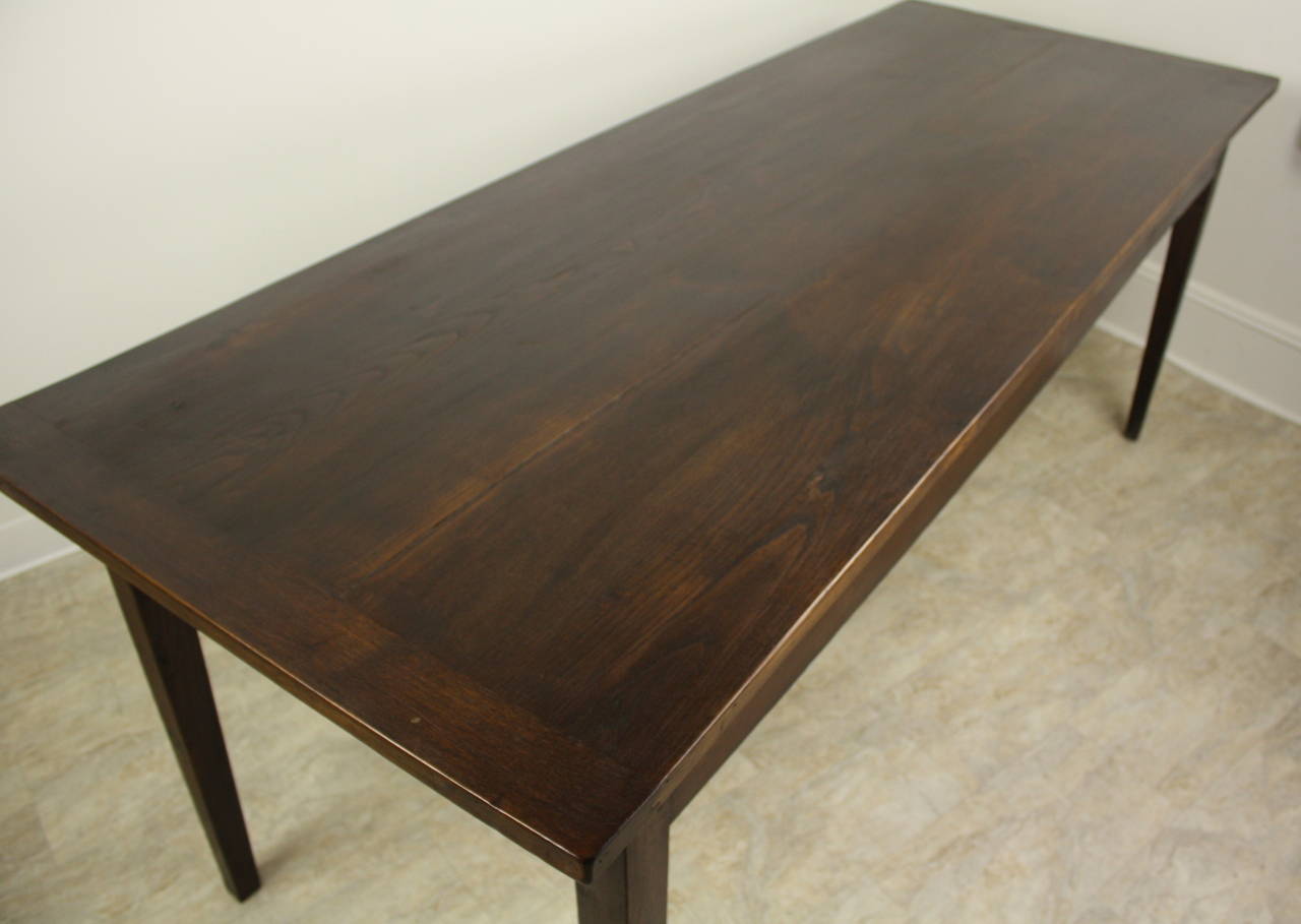 This handsome dark fruitwood farm table is sturdy and elegant. Slender tapered legs are pegged at the apron.  There is one small drawer on one end. The apron height is a good 25 1/4