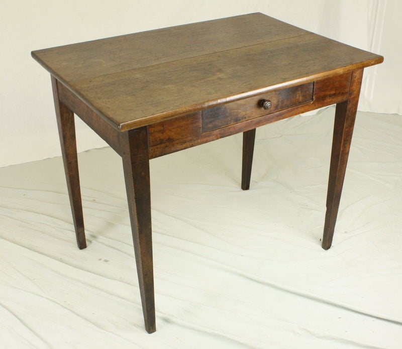 A small walnut writing table from 19th Century France. Nice walnut color with interesting old distress.  Height is perfect for a lamp or end table. Tapered legs and a single drawer contibute to a simple silhoutte.  Because of the smaller size, this