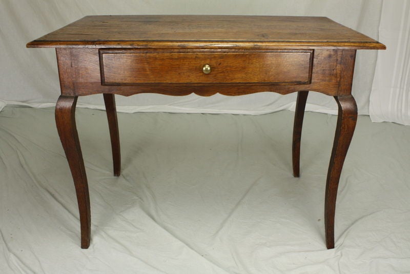 This is a treat to own. An 18th century side table from France. The oak is a beautiful warm color with a rich patina. Classic Louis XV details include cabriole legs and a scalloped apron. The top with some old markings, has an ogee edge. One drawer
