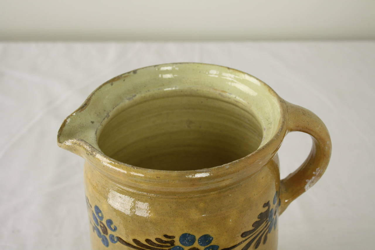 Ce charmant pichet en poterie de la région d'Alsace a une belle couleur et une décoration florale colorée. Ce pichet est de grande taille et convient comme décoration ou comme pichet ou vase classique.