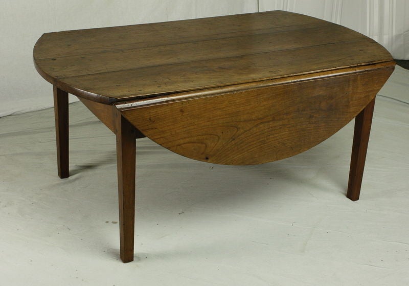 An antique dropleaf coffee table from France. Made of cherry with a warm color and patina. The almost round oval when opened is a very pretty shape. Drop leaves are both stylish and practical. With both leaves down, the table measures 46