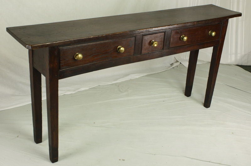 An antique console table from France with three drawers. Made of ash with a deep color and rich grain. The depth has been reduced to 14
