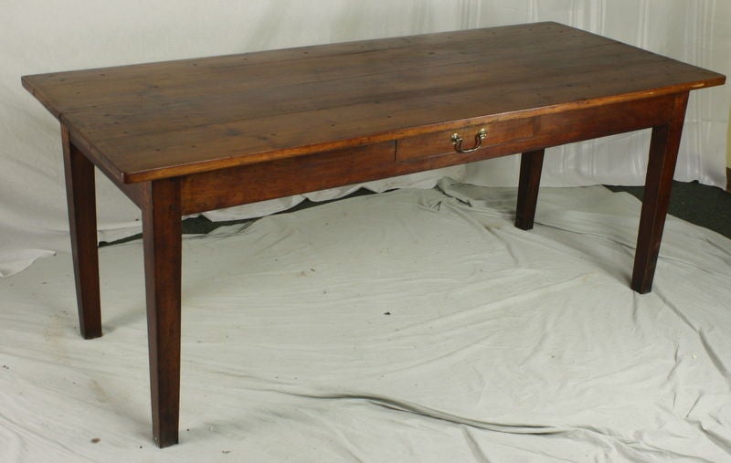 An antique country dining table from France. Made of cherry with wonderful color and patina. Two drawers, one on the side and one on the end. Apron height for knees is 24