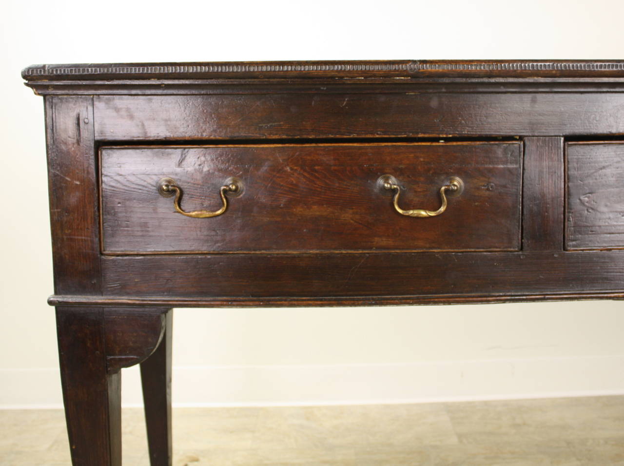 A very handsome early console, in a rich dark pine. The side aprons have an unusual scallop and very attractive corners enhance the connection on the front, from the leg to the base. The configuration of the three drawers, with the middle drawer a