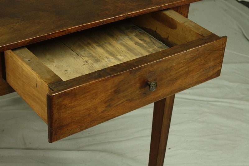An antique side table from France. Made of walnut in a beautiful color with a rich grain and a very good patina. One drawer with a pretty old knob. Height allows this to be a small desk.  Apron height for knees is 24