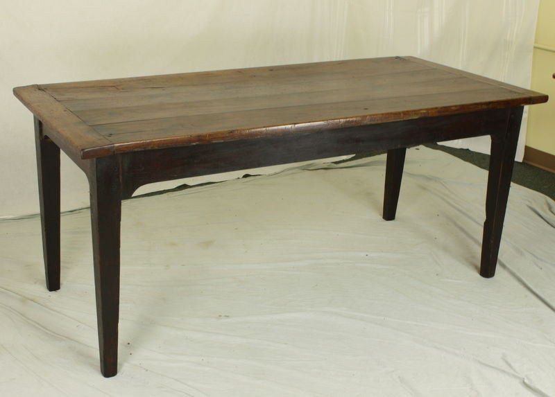 An antique farm table from France. Made of cherry with a thick top and breadboard ends. The top has a lovely color and is rich in wear and patina. There is an old patch on the top which we think adds lots of character. Base is stained a deeper