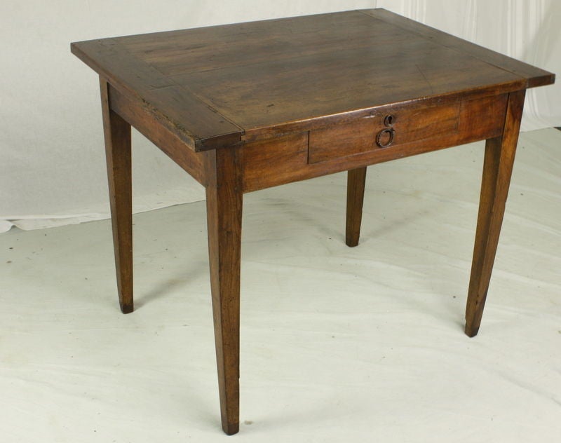An antique writing table or small desk from France. One drawer with the original wood escutcheon. The old iron pull was probably added later. The fruitwood has a beautiful color and rich patina. Very pretty thick top with breadboard ends. Could also
