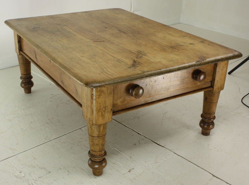 A very chunky farmhouse coffee table, reduced in height as all coffee tables are, for an informal country home.  Very pretty color, good waxed patina, interesting features of large drawer, great knobs, and very nice turned legs.