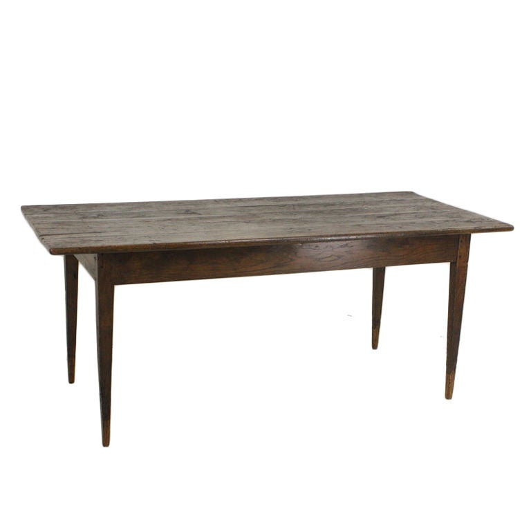 Early rustic-topped French country table. Very good-looking slender tapered legs on this conveniently sized-table, which offers a little extra depth for serving plates.  Classic dark oak color and patina, lovely graining.
