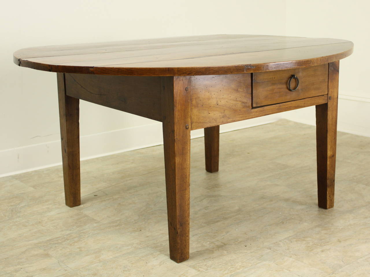 This coffee table has gorgeous cherry color and a charming oval design.  Classic tapered legs and one slightly offset drawer in the apron.  Some nice old distress in the top adds to the general character of the piece, although the highlight is truly