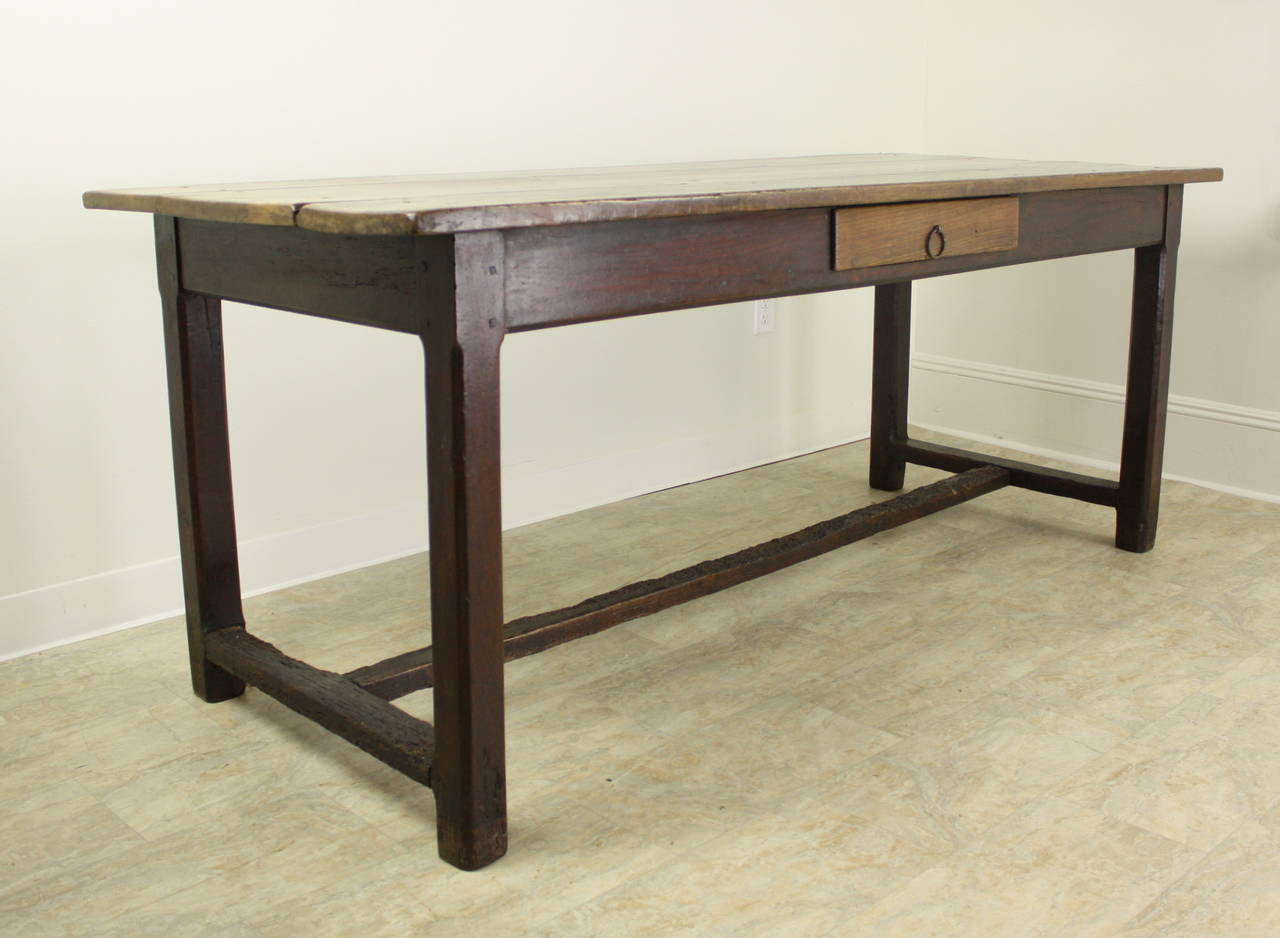 A lovely warmly colored cherry farm table with an interesting stretcher base. There are 64