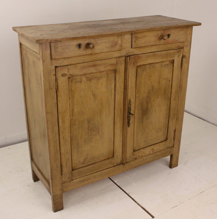 A simple smaller pine sideboard, for a cottage console look.  With two drawers and inner shelves, this server offers good storage space, for a small piece.  Waxed in a honey color, pretty brass escutcheon on the right door, with key. This piece