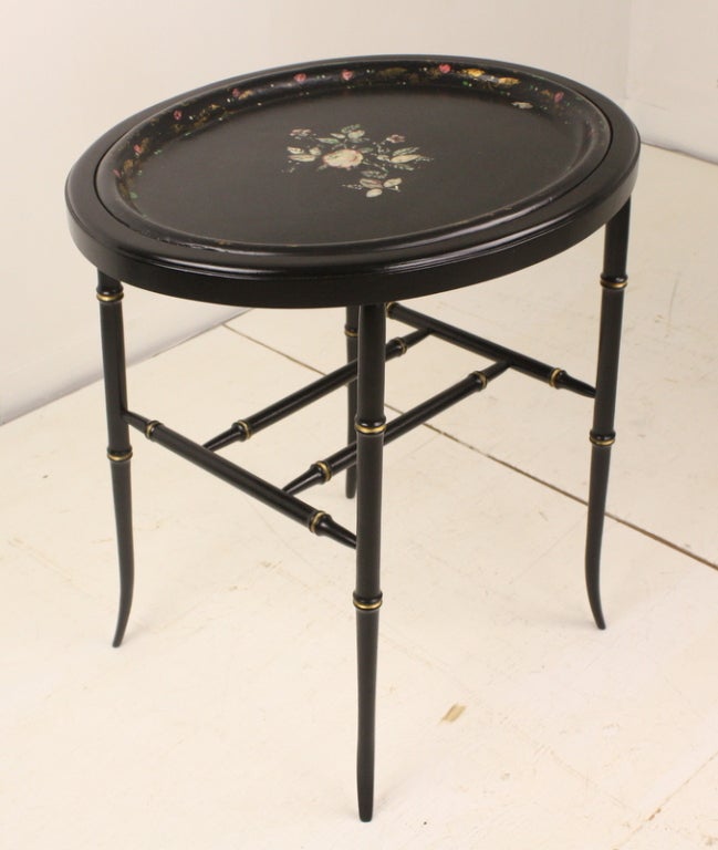 Antique oval tole tray on new stand made of black laquered wood and gilt.   The delicate mother of pearl inlaid roses in the center of the tray are complimented by the original hand painted floral design around the edge. The top has been completely