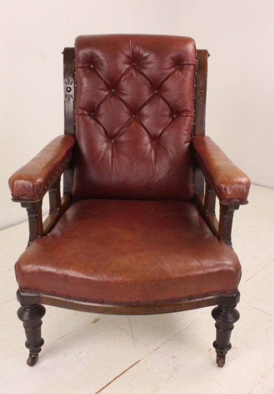 A very handsome gentleman's library chair, very roomy and comfortable, with a good, deep seat. The old leather is in good condition, the turned legs are very well-made, with attractive upholstery nails.  There is decorative carving on the top side