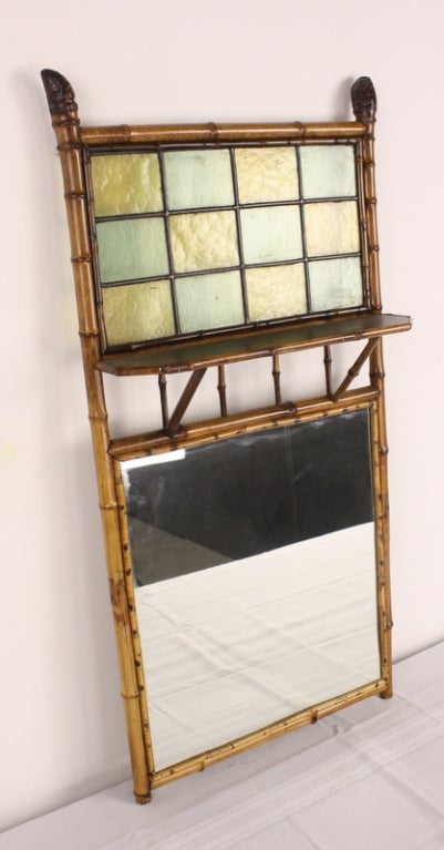 A very good and very decorative bamboo mirror, suitable for over a chest, in the bath, or just about anywhere. Extra touches are the attractive leaded colored glass section above the mirror, and the charming root-ends at the very top.
