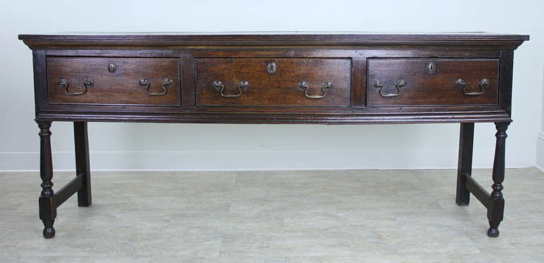 A dramatic, classic, 18thC oak dresser base, a great Georgian piece.  This is a nice long console, with three large drawers.  The hand-turned legs are lovely, and have the added visual enhancement of the stretchers on the ends.  Very well-made