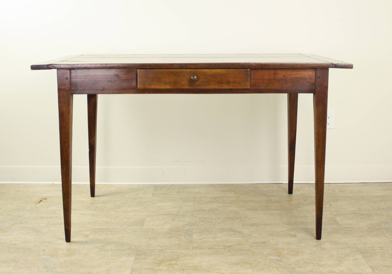 A splendid writing table in the warmest cherry with lovely grain and patina.  The thin elegant legs and single center drawer complete the look.  Apron height of 25.5