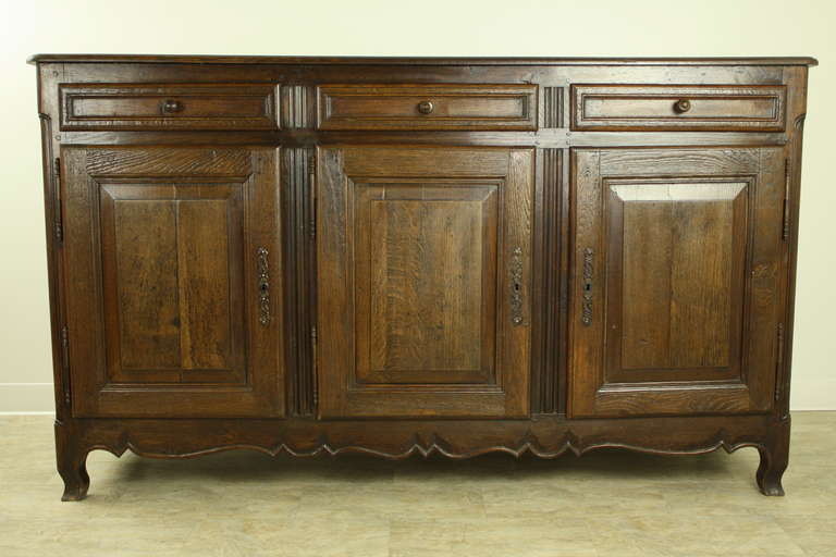 Dramatic piece with great storage in three shelved compartments with three drawers above. The doors are well panelled as are the sides. There is a simply shaped apron. Feet are well-shaped also. The modified vertical linen-fold carvings are