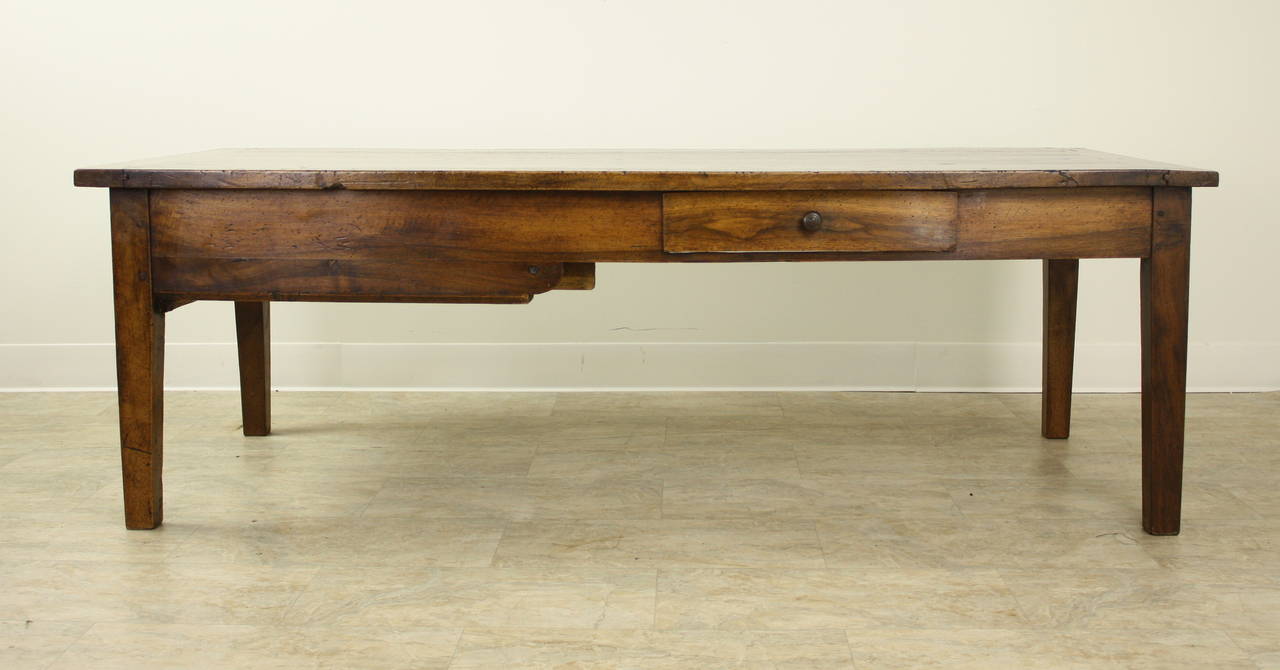 An nicely sized antique coffee table in well patinated, richly grained walnut. A small drawer on one side, as well as one deep storage drawer at the end. Interesting shaped apron and breadboard ends complete the look. A Classic!