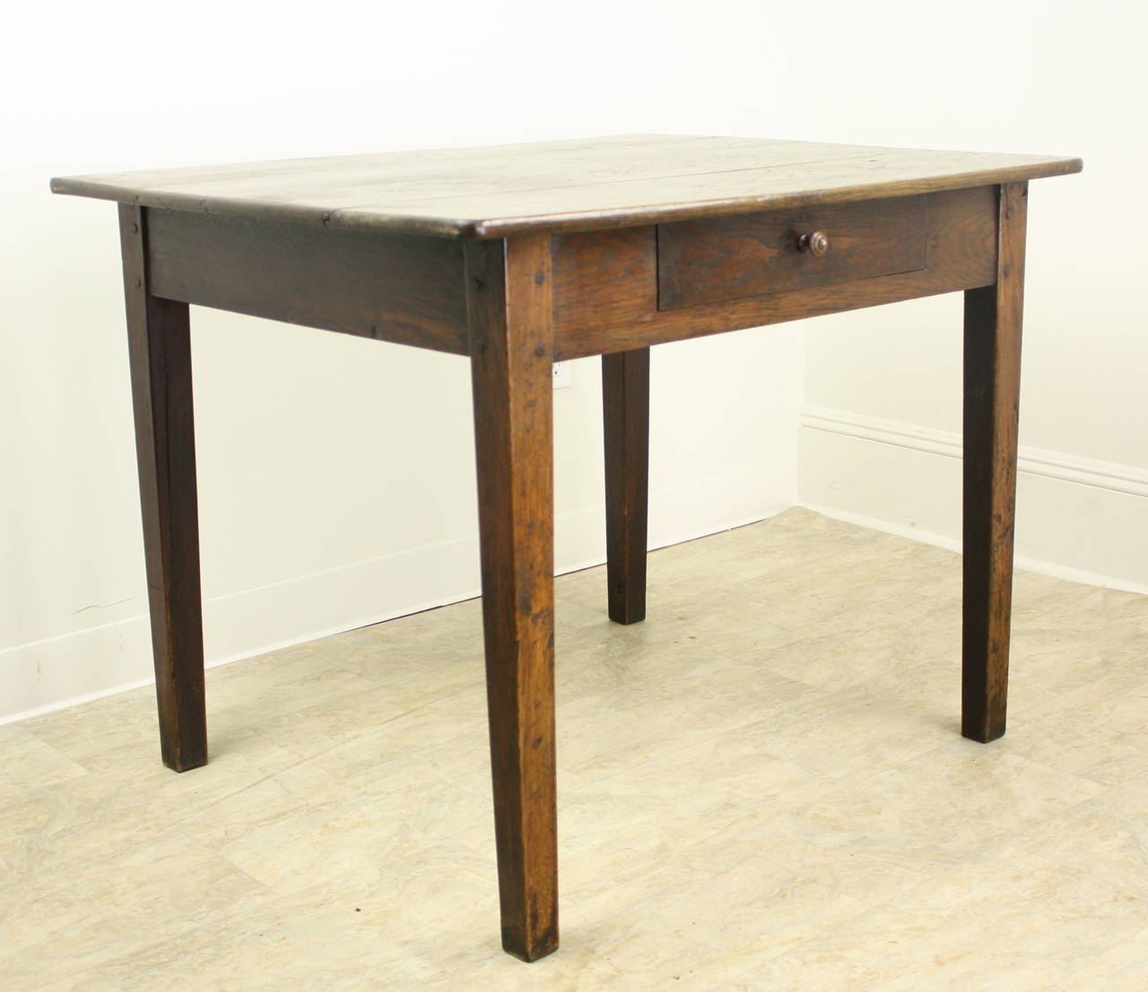 A handsome dark chestnut writing table with generous proportions on sturdy tapered legs.  The wood has nice color and patina, and the extra depth of the piece makes it an elegant and functional work surface.  One single divided drawer. At 24