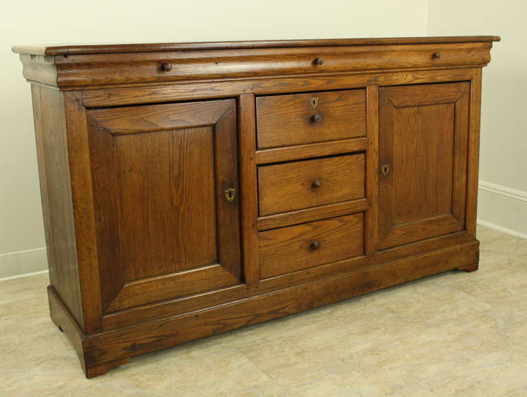 This is a very warm-colored oak, exhibiting the classic Louis Philippe decorative elements.  The shaped top drawer is faux, and the usable drawers run down the middle of the piece between the side storage compartments. This simple enfilade is