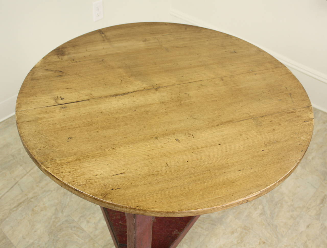 An antique Welsh cricket table. The base has the old red paint, and the top is a honey pine, both rich in wear and patina. Makes a terrific lamp table.