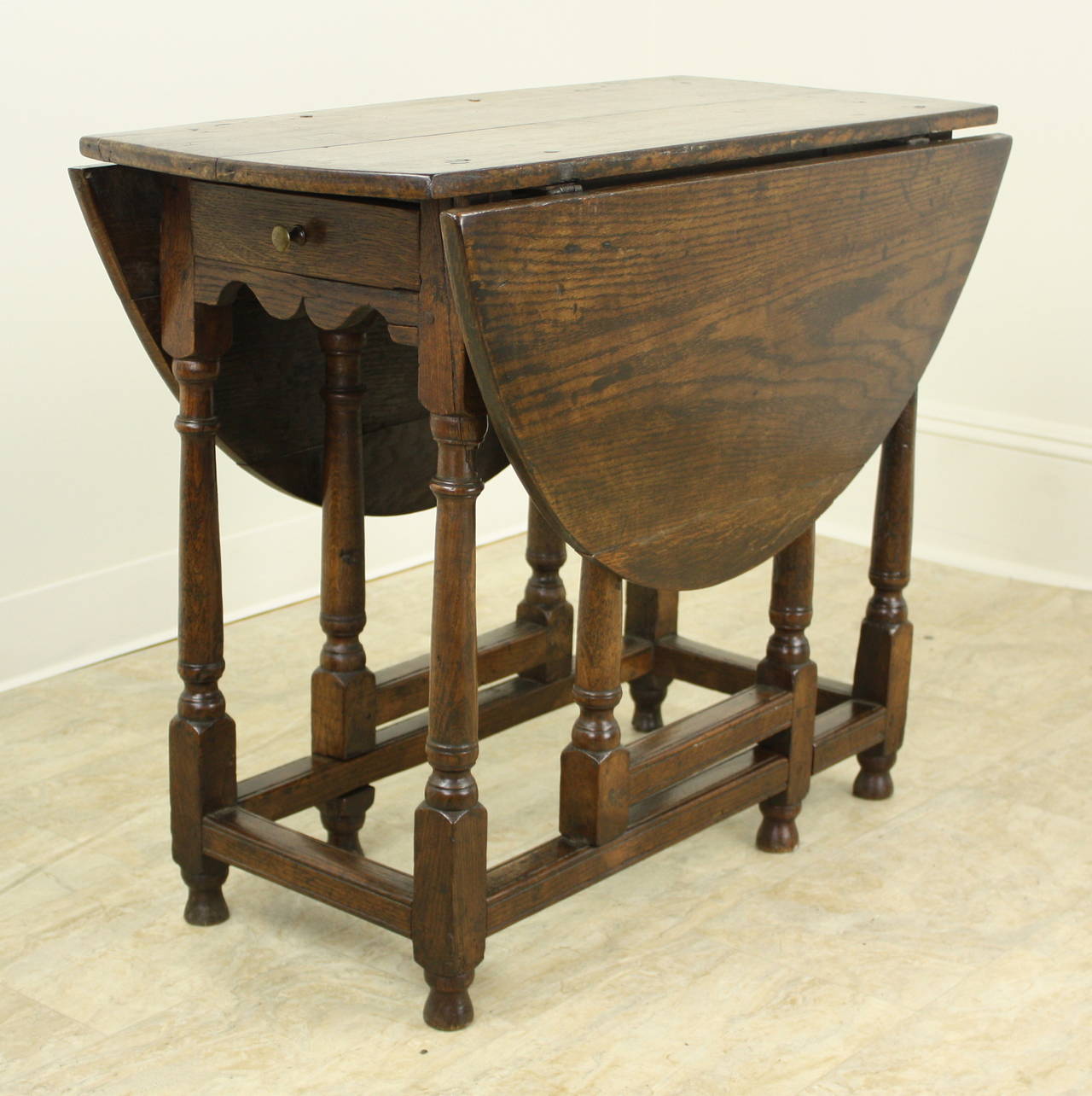 A charming period oak Gateleg table, with a small size that allows a multitude of uses.  Large end table, side table, lamp table, or a small library table for an apartment.  Some old distress on top adds character. When closed, the table measures