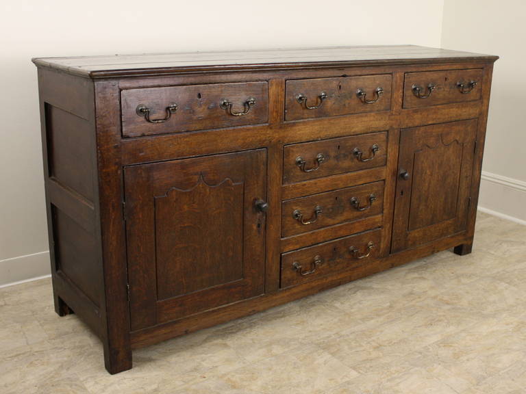 Terrific antique look, period oak is outstanding and always very impressive. This long buffet, or Enfilade, offers inside storage behind the two side doors, with three drawers across the top and three down the middle.  Patina and grain live up to