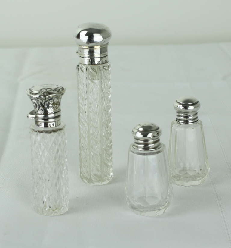 A delightful collection of four small perfume bottles, all with hallmarked silver tops. Measurement below is for the biggest bottle, manufactured in Birmingham and dated 1898. The medium tall one measures 3.25 H x 1