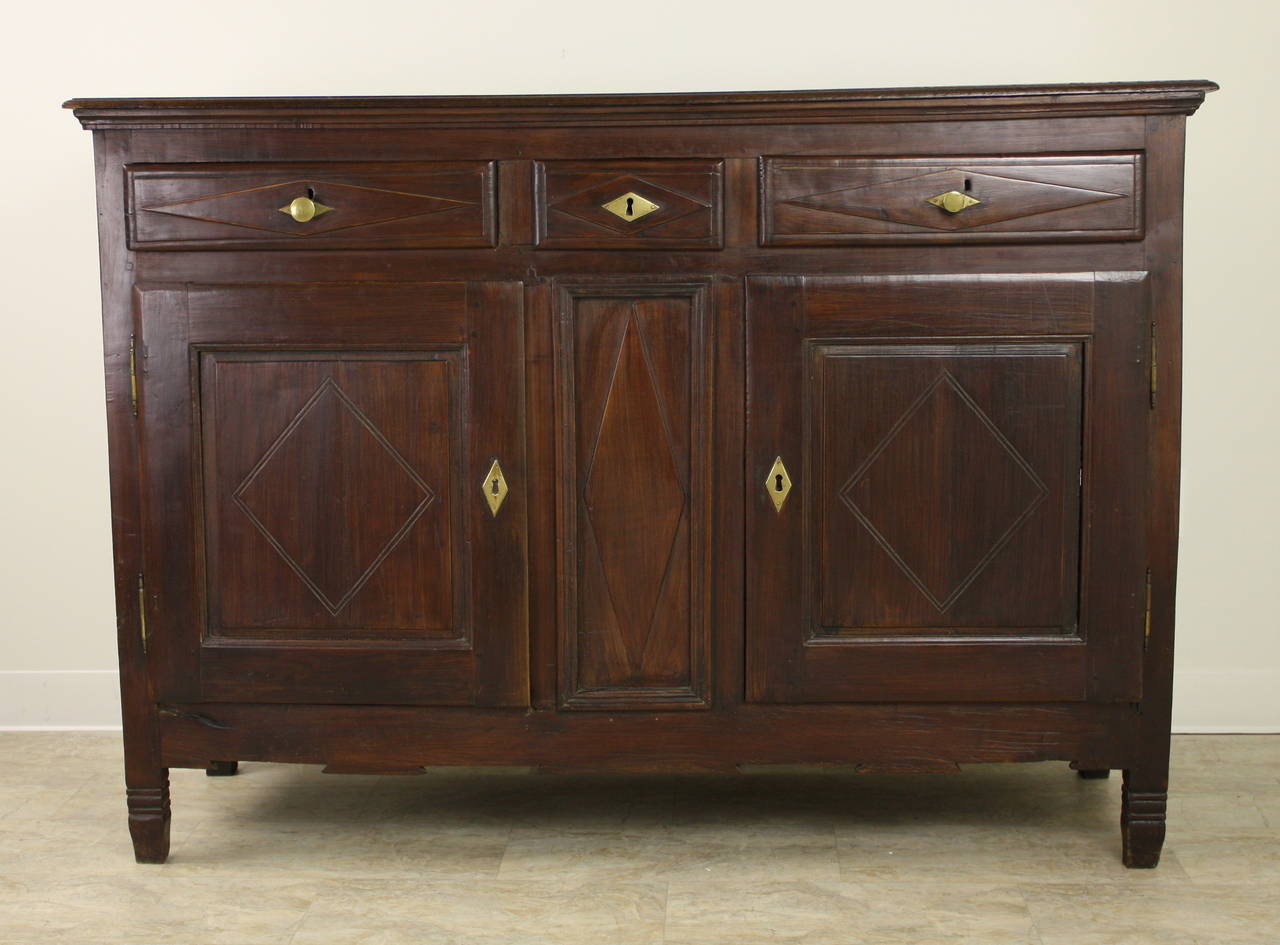 An antique chestnut buffet from France. Note the carved diamond pattern on the drawers and doors.  At 58