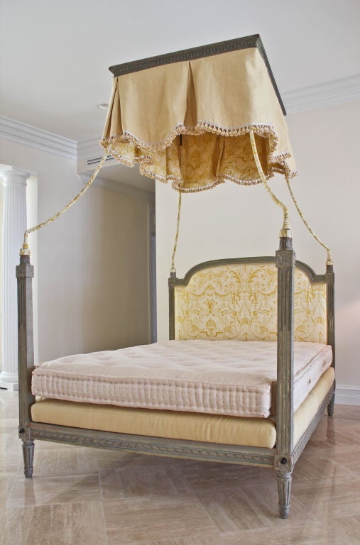 A very nicely designed period Louis XVI style bed with a rectangular crown supported by curving iron atop carved wooden posts. Original grey - green paint on most of the surface, with superb patina. The bed has had modifications and comes with a